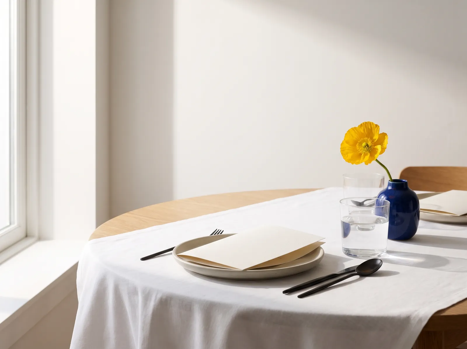Gedeckter Tisch mit weißem Leinen, leerer Speisekarte und einer gelben Blume