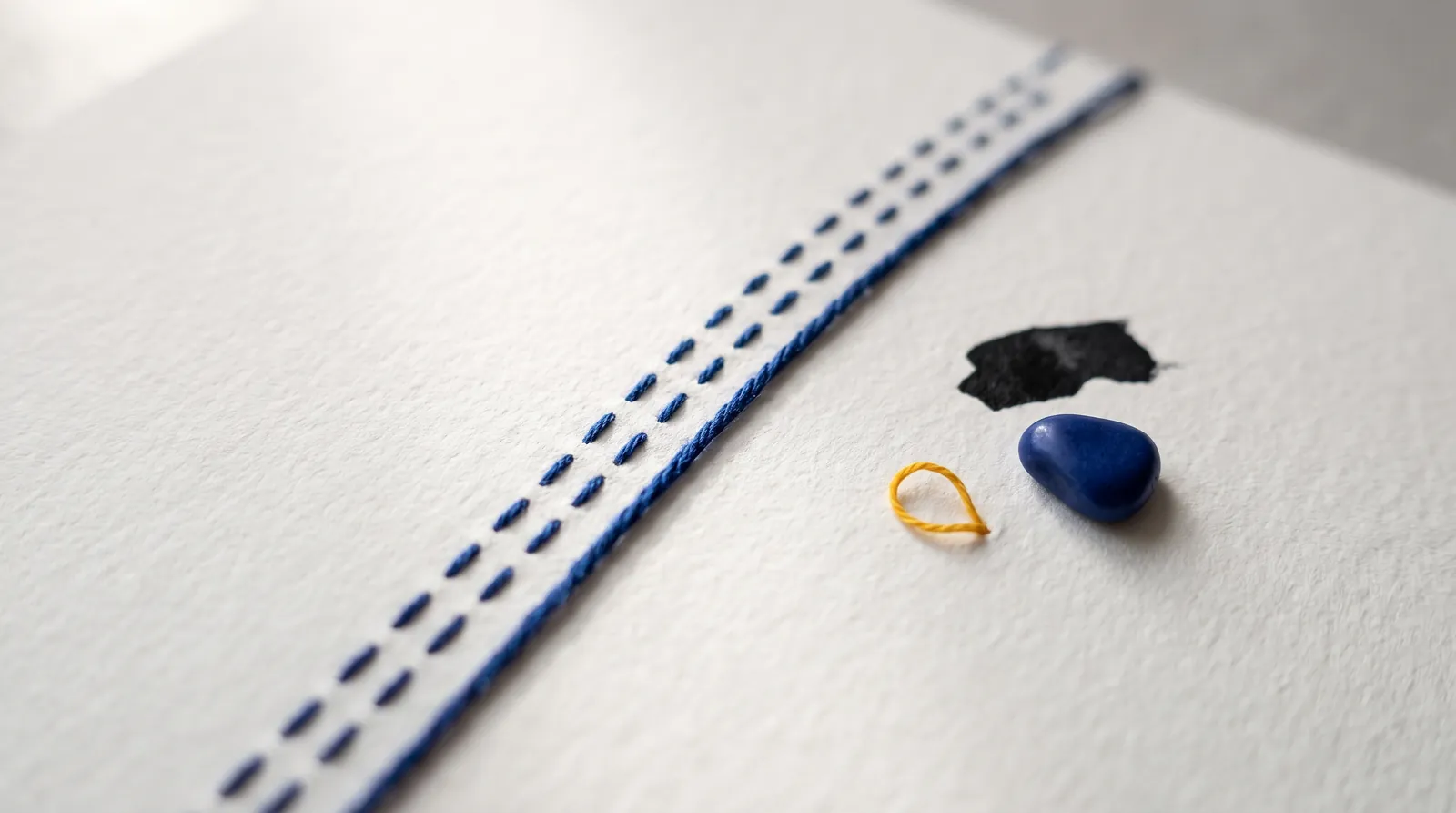 Straight seam of cobalt blue thread on light paper